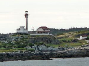 Red and white lighthouse and buildings on a the coast