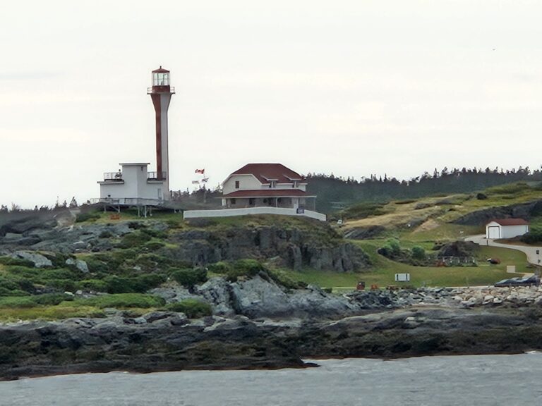 Red and white lighthouse and buildings on a the coast
