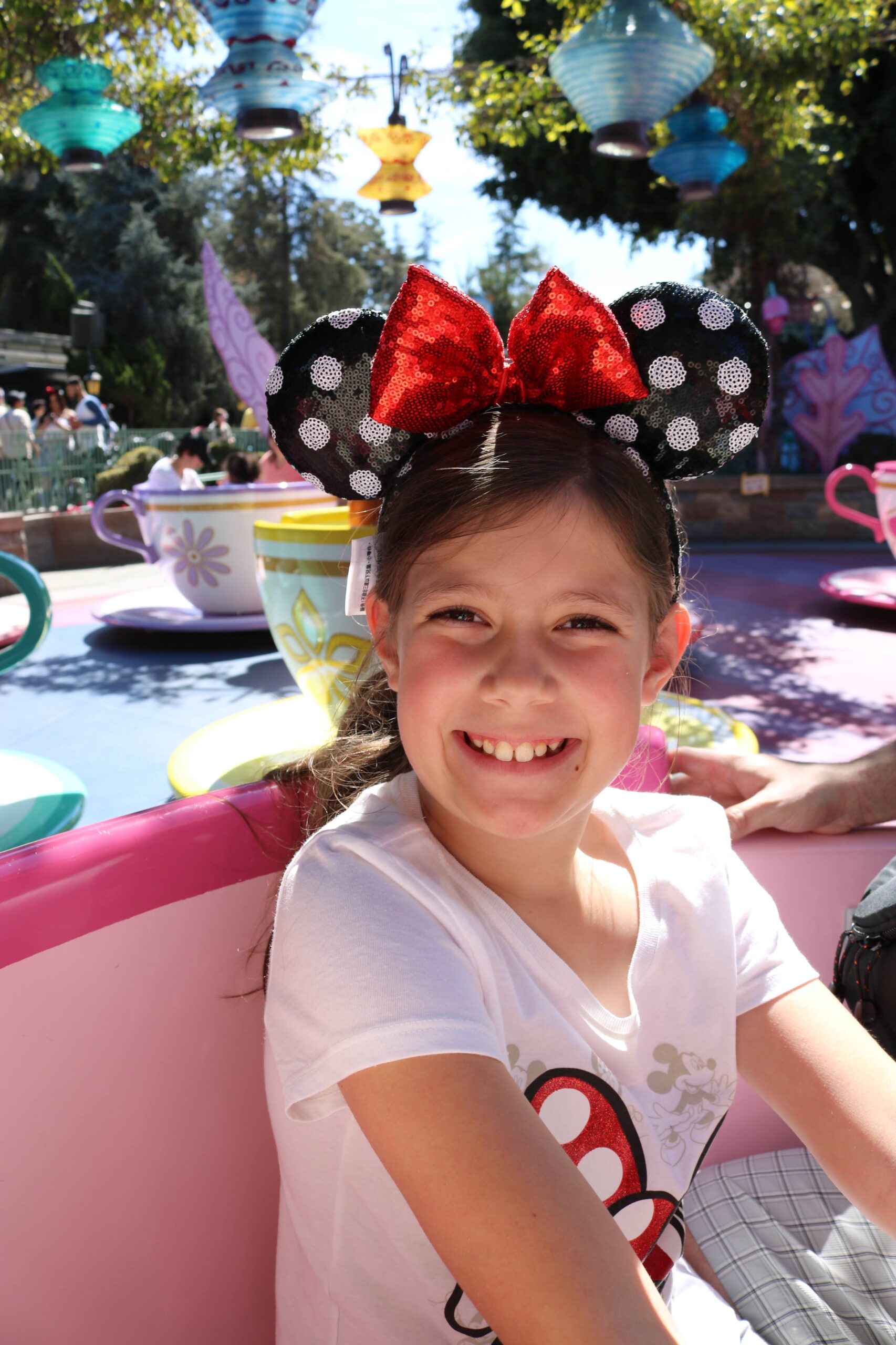 Young girl with Minnie Mouse ears riding tea cups in Disneyland